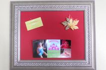 Framed cork bulletin board covered in red fabric.
